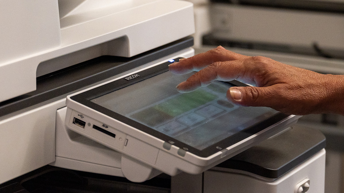 Hand reaching toward a printer display.