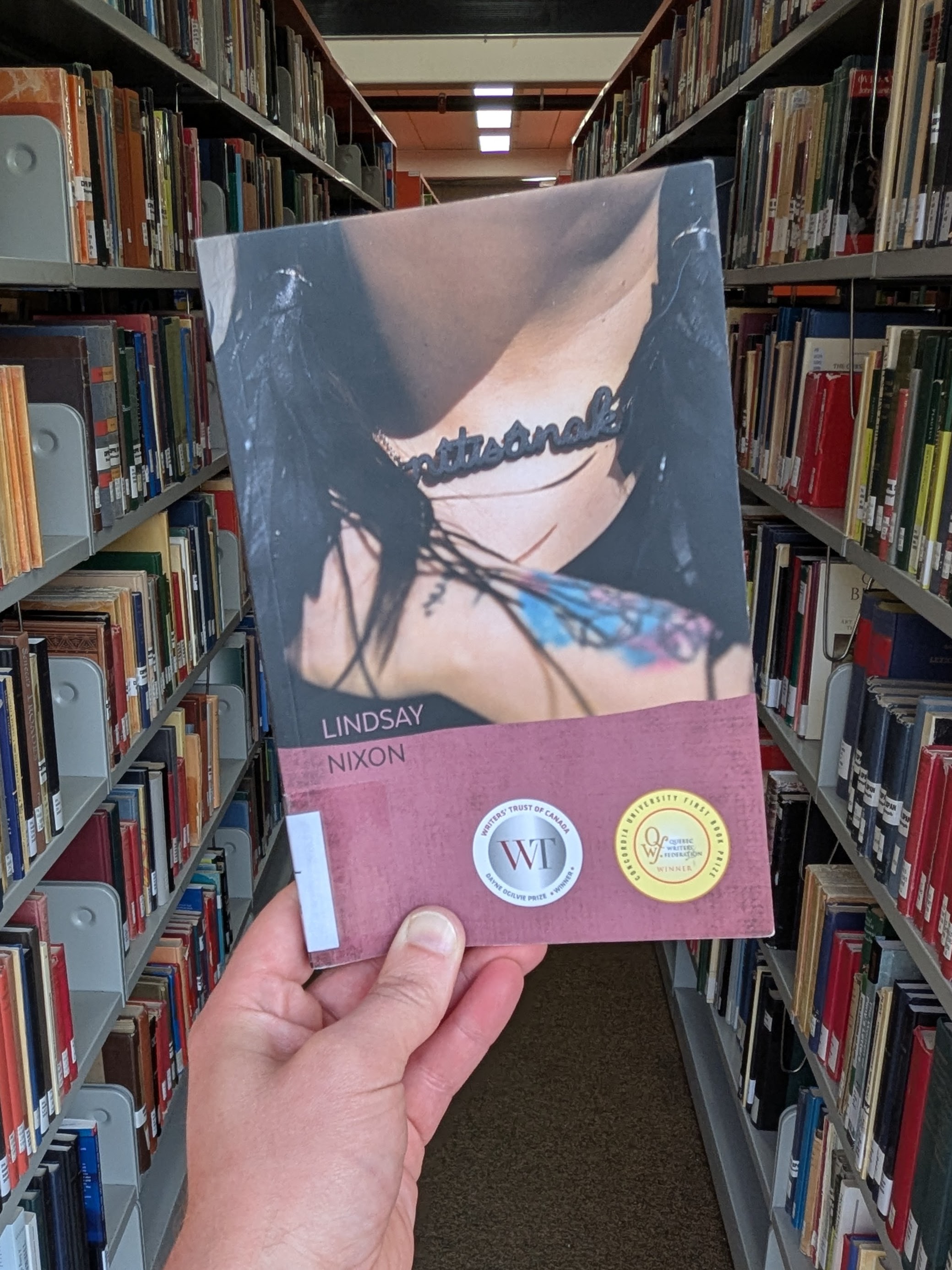 A person wearing a neclace with the book's title on the cover.