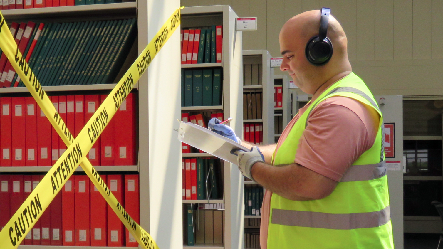 A man in a construction vest writing on a clipboard.