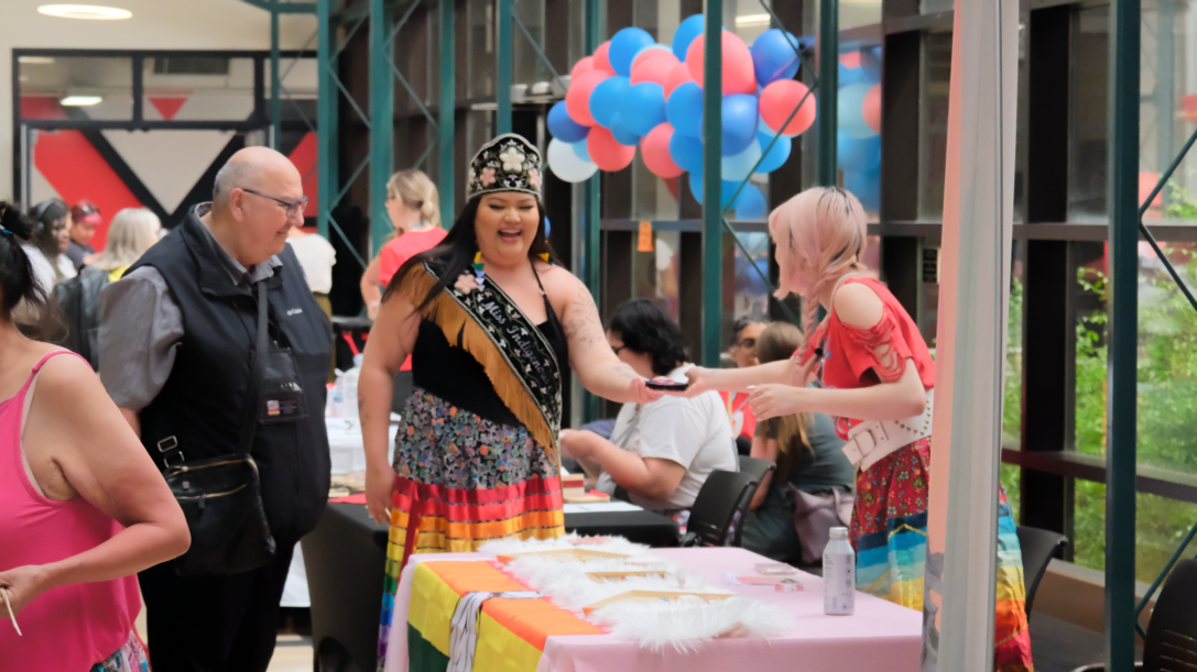 People gathered around a colourful table at the Indigiqueer Maker's Market.