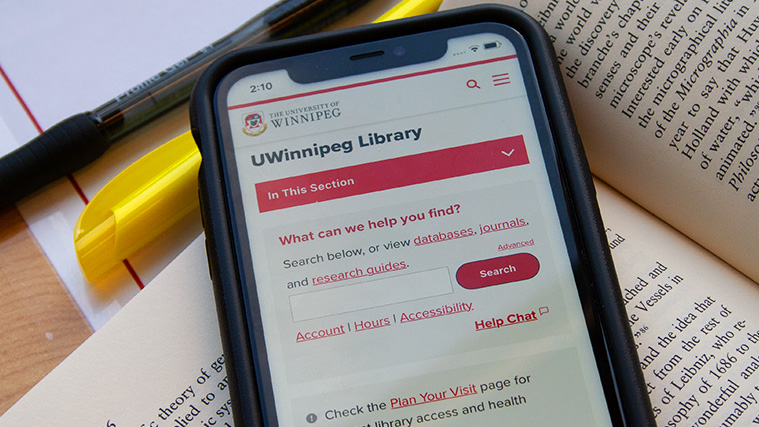 Smartphone with the library website loaded, resting on an open textbook.