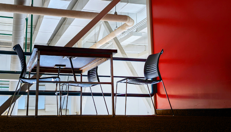 A brightly lit study space with a big red wall behind it.