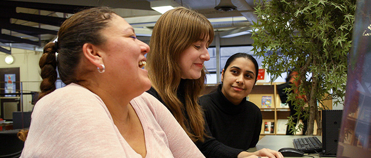 A group of three students in front of a computer in the library